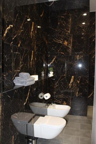 a black marble bathroom with a sink and a toilet at Vārves Muiža in Vārve