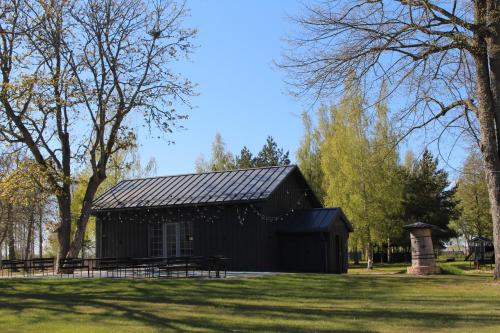 a black building in a park with trees at Vārves Muiža in Vārve