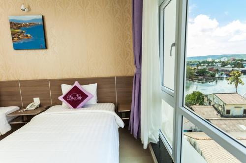 a hotel room with two beds and a window at Blue Sky Phu Quoc Hotel in Phu Quoc