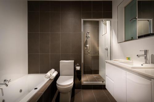 a bathroom with a toilet and a tub and a sink at Crest On Barkly Serviced Apartments in Melbourne