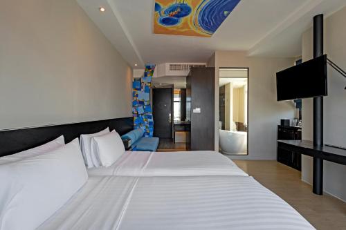a hotel room with a bed and a television at Siam@Siam Design Hotel Pattaya in Pattaya Central