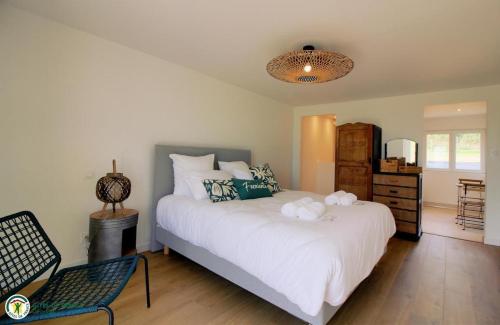 une chambre avec un grand lit blanc et une chaise dans l'établissement Cottage RG, à Lamothe-Landerron