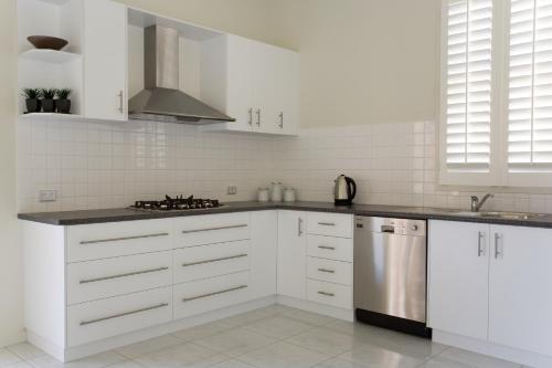 a kitchen with white cabinets and a stainless steel refrigerator at Sabina on Little Myers in Geelong