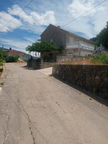 an empty street with a stone wall and a house at Apartman Tomas in Trebinje
