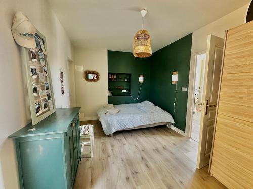 a bedroom with a bed and a green wall at L 'Émeraude, appt avec terrasse proche de la plage in Asnelles
