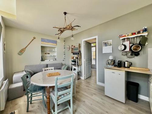 a kitchen and living room with a table and a kitchen and a dining room at L 'Émeraude, appt avec terrasse proche de la plage in Asnelles
