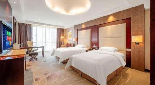 a bedroom with two beds and a desk and a television at Northwest Petroleum Hotel in Ürümqi