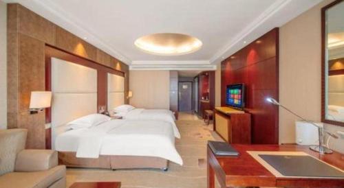a bedroom with a large white bed and a tv at Northwest Petroleum Hotel in Ürümqi