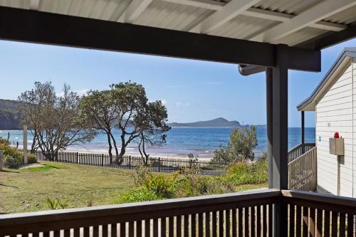 a view of the beach from the porch of a house at Reflections Seal Rocks - Holiday Park in Smiths Lake