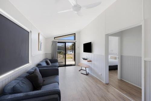 a living room with two couches and a bed at Reflections Seal Rocks - Holiday Park in Smiths Lake