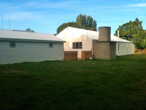 a white house with a garage and a grass yard at Taringatura Backpackers in Pukearuhe