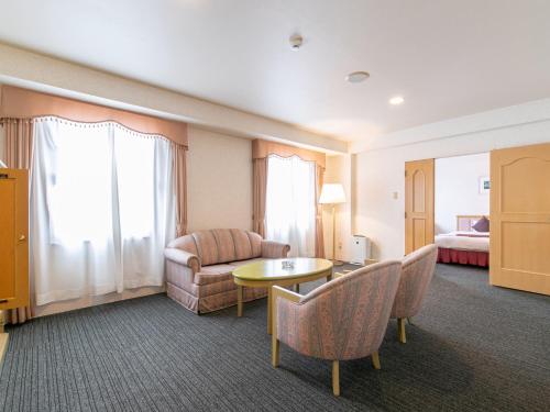 a hotel room with a couch and a table at Hotel Verfort Hyuga in Hyuga