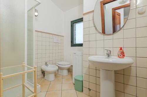 Un baño con lavabo, inodoro y espejo. en Oltre Casa, en Porto San Paolo