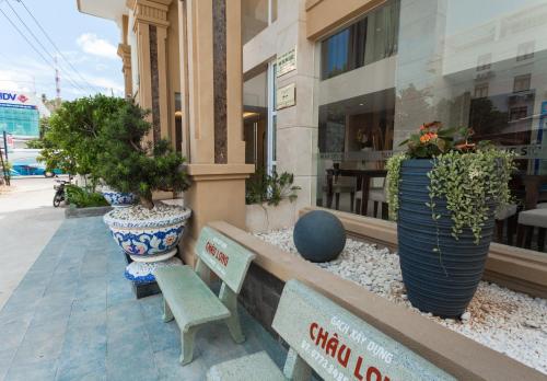 a building with two benches and potted plants on a sidewalk at Blue Sky Phu Quoc Hotel in Phu Quoc