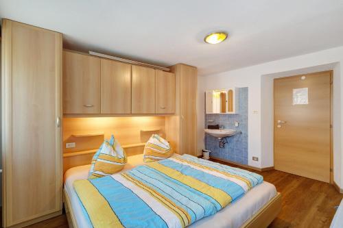 a bedroom with a large bed with striped pillows at Pension Waldheim Apartments in San Giacomo