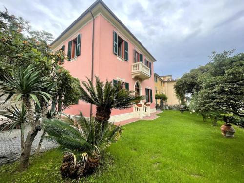 a pink house with palm trees in front of it at Garden Villa by the sea, Mesco 60 in Monterosso al Mare