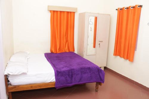 a bedroom with a bed with an orange curtain at SUNSHEE COFFEE PLANTATION HOMESTAY VILLA Madikeri in Madikeri