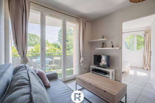 a living room with a couch and a tv at R'Apparts T2 L'Echappée Douce in Sassenage