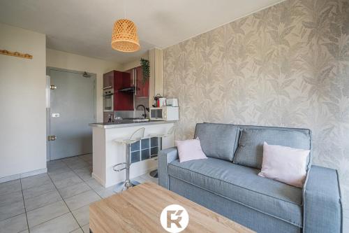 a living room with a blue couch and a kitchen at R'Apparts T2 L'Echappée Douce in Sassenage