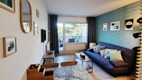un salon avec un canapé bleu et une fenêtre dans l'établissement Appartement avec Piscine, Quartier calme proche centre et plages d'Antibes, à Antibes