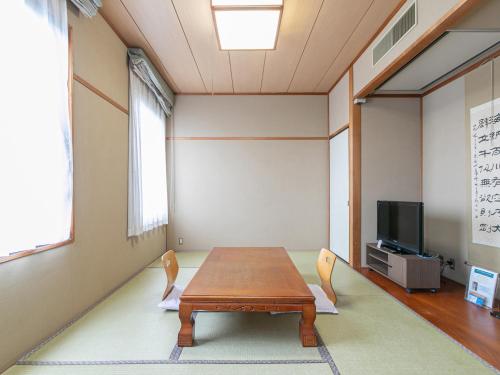 a room with a table and chairs and a tv at Hotel Verfort Hyuga in Hyuga