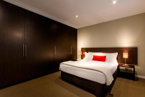 1 dormitorio con cama grande y almohada roja en Crest On Barkly Serviced Apartments, en Melbourne