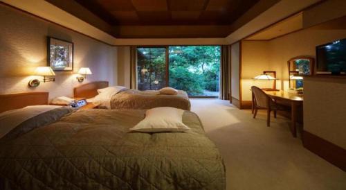 a hotel room with two beds and a desk and a table at Shiratamano Yu Kahou in Shibata