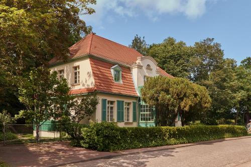 ein Haus mit rotem Dach und grünem Zierstreifen in der Unterkunft Willa Deco Sopot by Downtown Apartments in Sopot