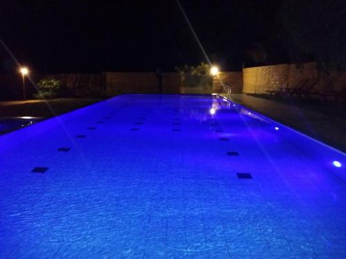 a large swimming pool at night with blue lights at Roshanne Beach Resort in Kalpitiya