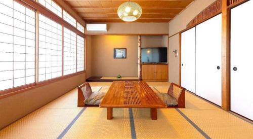 a room with a wooden table and two chairs and windows at Yukemuri no sato azumaya in Beppu