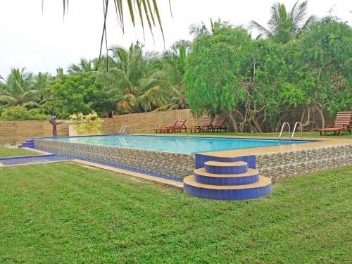 a swimming pool in a yard with chairs and trees at Roshanne Beach Resort in Kalpitiya