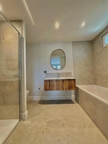 une salle de bain avec une baignoire, un lavabo et un miroir dans l'établissement Villa d'exception au bord du lac, à La Teste-de-Buch