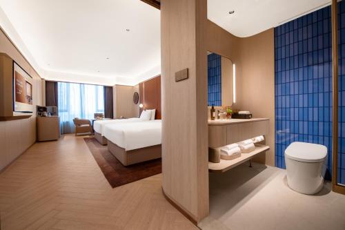 une chambre d'hôtel avec un lit et une salle de bain dans l'établissement Crystal Hotel Qingdao The Mall of Splendors, à Qingdao