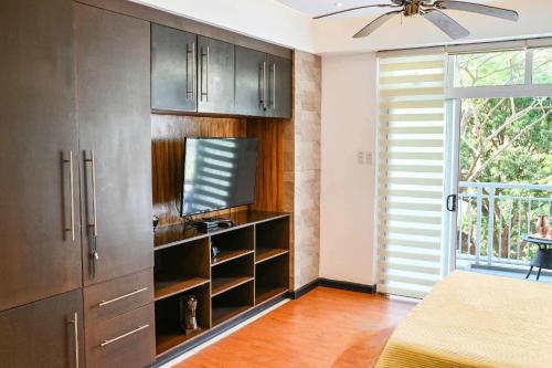 a kitchen with brown cabinets and a tv and a window at 1BR at Jacana B Pico de Loro in Nasugbu