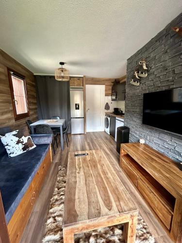 un salon avec un canapé et une télévision dans l'établissement Appartement rénové au pied des pistes avec piscine, sauna, linge inclus et animaux acceptés, à Flumet