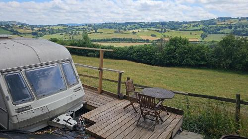Una camioneta estacionada en una plataforma de madera con una mesa. en Cosy Caravan Walkers Ramblers Fishermen Cyclists, en Abermule