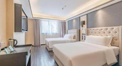 a hotel room with two beds and a desk at Xana Hotelle Zhuhai Gongbei Port in Zhuhai
