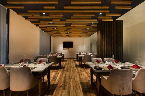 a dining room with tables and chairs and a screen at VERTTU Horizon Delhi Airport Free Airport Pick Up in New Delhi