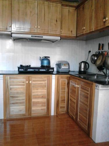 a kitchen with wooden cabinets and a stove top oven at Manh Duyen Garden Homestay in Phú Quốc