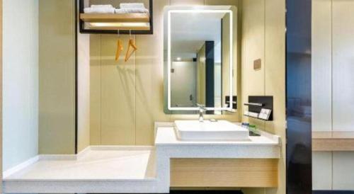 a bathroom with a sink and a mirror at Borrman Hotel Xiamen Xiang'an Maxiang in Xiamen
