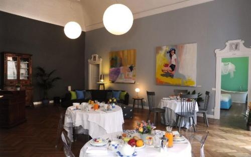 une salle à manger avec des tables blanches, des chaises et des peintures dans l'établissement B&B Casa Fenoglio, à Vintimille