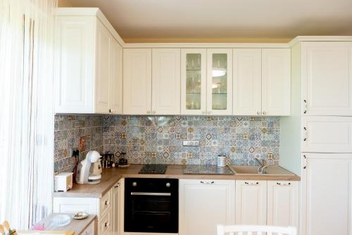 cocina con armarios blancos y lavavajillas negro en Ваканционен апартамент Делфин 14 Holiday Apartment Dolphin 14, en Kavarna