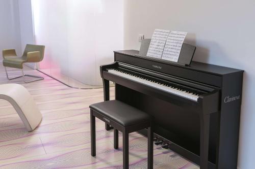 a black piano with a stool next to a chair at nhow Berlin in Berlin