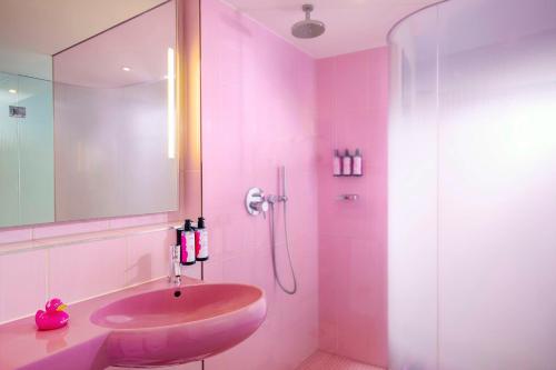 a pink bathroom with a sink and a shower at nhow Berlin in Berlin