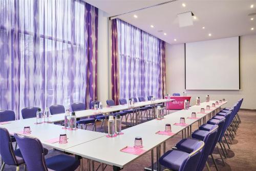a conference room with tables and chairs and a screen at nhow Berlin in Berlin