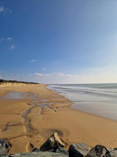 a beach with rocks in the sand and the ocean at Maison typique 6 couchages oleronaise au cœur de l'île d'oleron in Saint-Pierre-dʼOléron