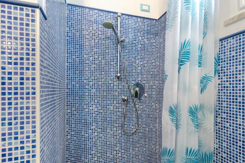 a bathroom with a shower with blue tiles at Hostdomus - Altrove Apartment in Villanova dʼAlbenga