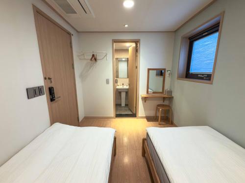 a room with two beds and a bathroom with a sink at Guest House Brick in Jeju