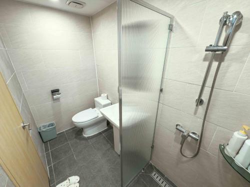 a bathroom with a toilet and a glass shower stall at Guest House Brick in Jeju