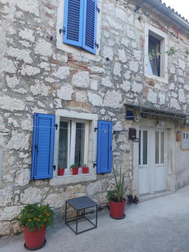 a building with blue shutters and a table in front of it at Apartman Karo in Vrsar